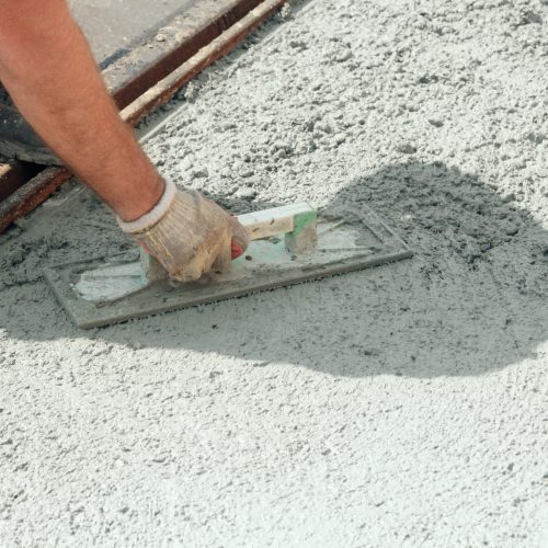 Construction worker leveling concrete pavement.